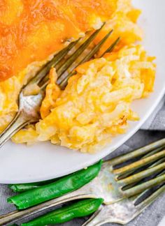 an omelet on a white plate with silverware and green beans next to it