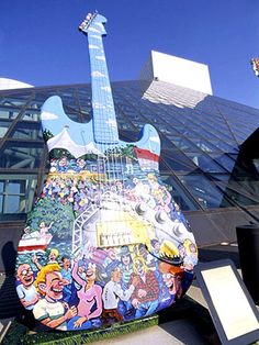 an electric guitar is on display in front of a large building with cartoon characters painted on it