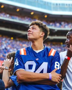 two young men standing next to each other in front of a crowd at a football game