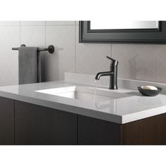 a bathroom sink sitting under a mirror next to a faucet and towel rack