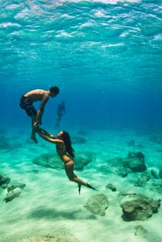 two people are swimming in the ocean with rocks and corals on the bottom of the water