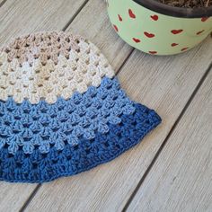 a crocheted hat sitting on top of a wooden table next to a potted plant