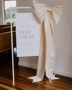 a white sign with a bow on it sitting in front of a church pews