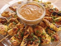 chicken skewers and dipping sauce on a glass platter