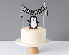 a birthday cake with a penguin topper on it