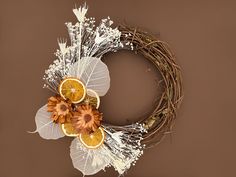 a wreath with dried oranges and flowers on it is shown in front of a brown background