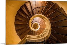 a spiral staircase in an old building with yellow walls and wooden railings that lead up to the second floor