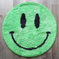 a green smiley face rug sitting on top of a wooden floor next to a wood floor