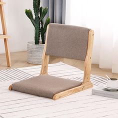 a wooden chair sitting on top of a rug next to a potted green plant