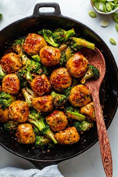 broccoli and meatballs in a skillet with a wooden spoon on the side