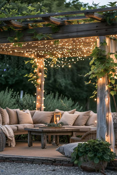 an outdoor seating area is lit up with fairy lights and greenery on the pergoline