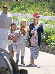 the family is walking down the street with their baby and toddler dolls in their arms