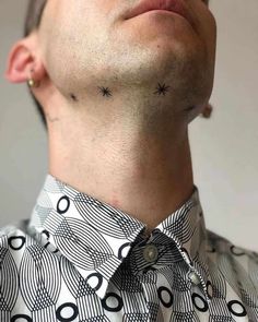 a man with tattoos on his neck wearing a dress shirt and looking up at the sky