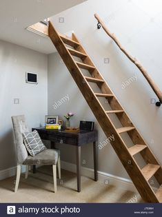 a wooden staircase leading up to a desk and chair in a home office with white walls