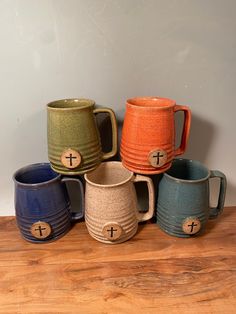 several different colored mugs sitting on top of a wooden table