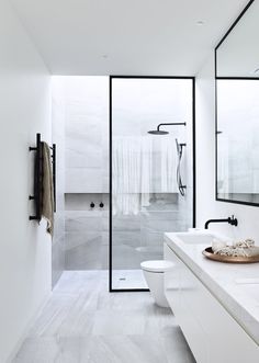 a white bathroom with two sinks and a large mirror on the wall next to it