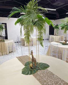 a giraffe statue sitting on top of a table next to a palm tree