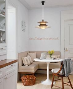 a kitchen with white walls and wooden floors, along with an l shaped table in the center