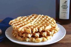 a waffle sitting on top of a white plate next to a bottle of syrup