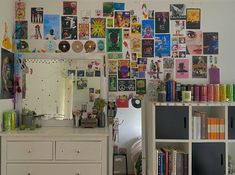 a room with a dresser, mirror and bookshelf filled with various posters on the wall