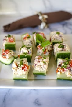 cucumber and cheese appetizers on a plate with a knife in the background