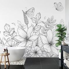 a bathroom with black and white flowers on the wall next to a bathtub filled with pebbles