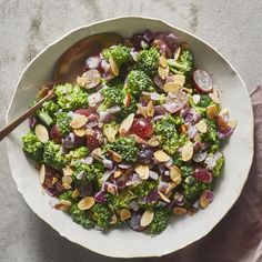 a white bowl filled with broccoli, onions and almonds on top of a table