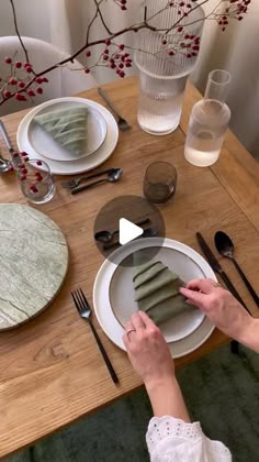 the woman is setting the table with her placemats and napkins on it