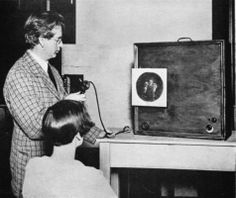 an old black and white photo of two women looking at a piece of art on a table