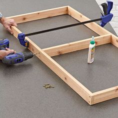 a man is working on wood frame with glue and screwdrivers next to it