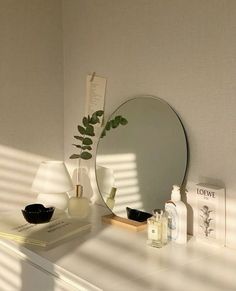 a white dresser topped with a mirror next to a plant