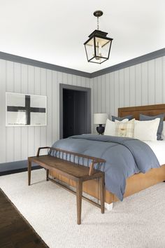 a bedroom with blue and white striped wallpaper, a wooden bed frame, and a bench in front of the bed