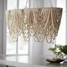 a chandelier hanging from the ceiling in a room with white walls and windows