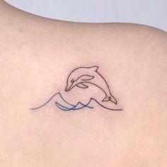 a small dolphin tattoo on the back of a woman's upper arm and shoulder