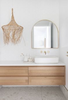 a bathroom with two sinks, a mirror and a light fixture hanging from the ceiling