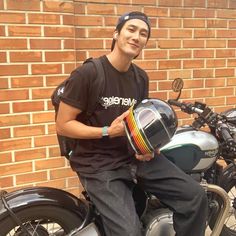 a man sitting on top of a motorcycle wearing a helmet and holding a colorful tube