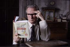 an older man sitting at a table with a book in his hand and looking through it