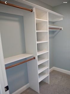 an empty walk in closet with white shelving and copper rails on the door handles