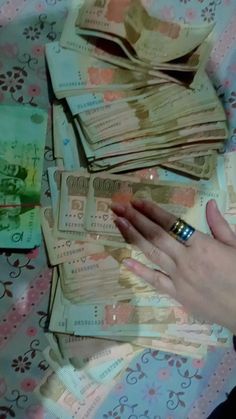 a person's hand on top of stacks of money