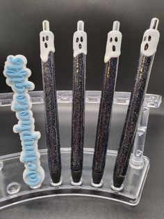 four toothbrushes with black and white glitter on them in a clear holder,