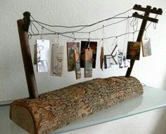 a piece of wood sitting on top of a glass shelf with pictures hanging from it