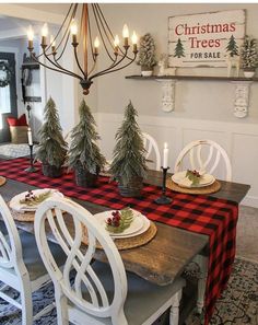 a dining room table decorated for christmas with pine trees on the top and plaid runner