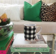 a coffee table topped with books and a vase filled with flowers next to a couch