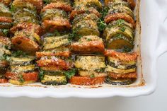 a casserole dish with zucchini, tomatoes and parmesan cheese