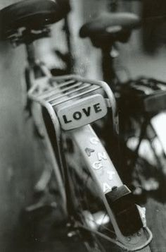 a black and white photo of a bicycle with love written on the handlebars