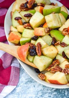 an apple salad with pecans, apples and raisins in a white bowl