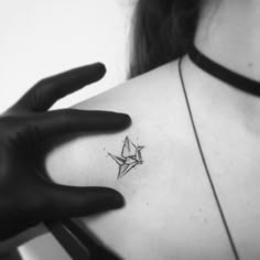 a woman's upper arm with a small star tattoo on the left side of her shoulder