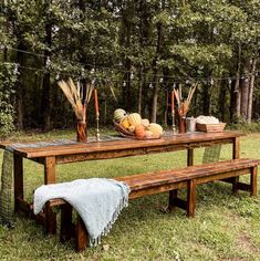 a picnic table set up in the woods with pumpkins and other autumn decorations on it