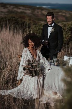 a man in a tuxedo standing next to a woman sitting on a chair