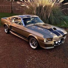 an old mustang car parked in the driveway